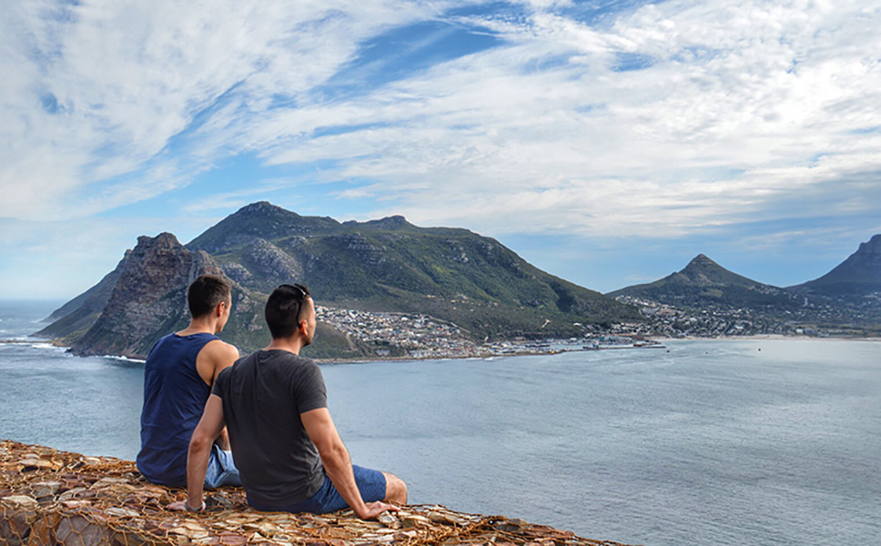 A couple sit on a wall and enjoy the view over Cape Town.