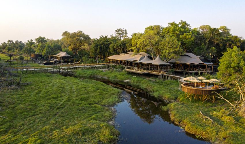 Aerial view of Xigera Safari Lodge in Botswana’s Okavango Delta, surrounded by lush greenery and winding waterways.